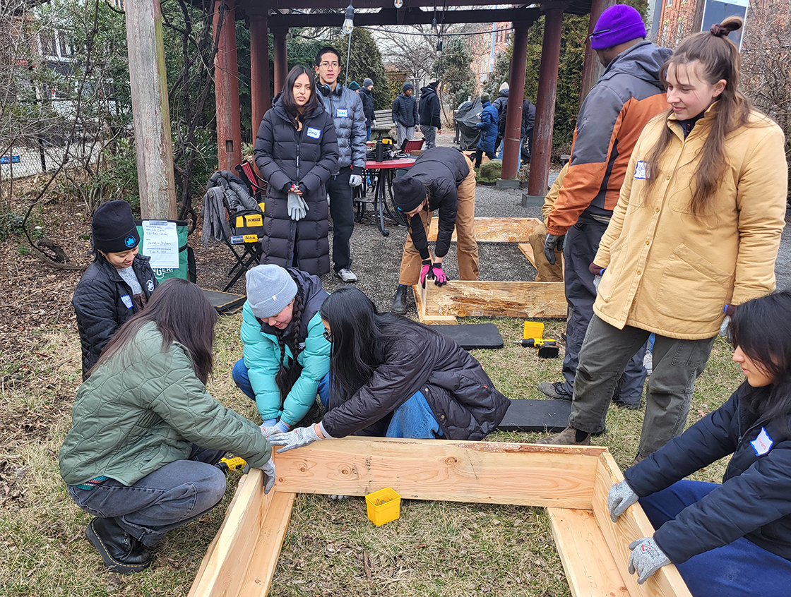 A large group of smiling people standing, sitting, and kneeling in a large bright room. Some people are holding garden recognition awards and signs saying I love my garden.